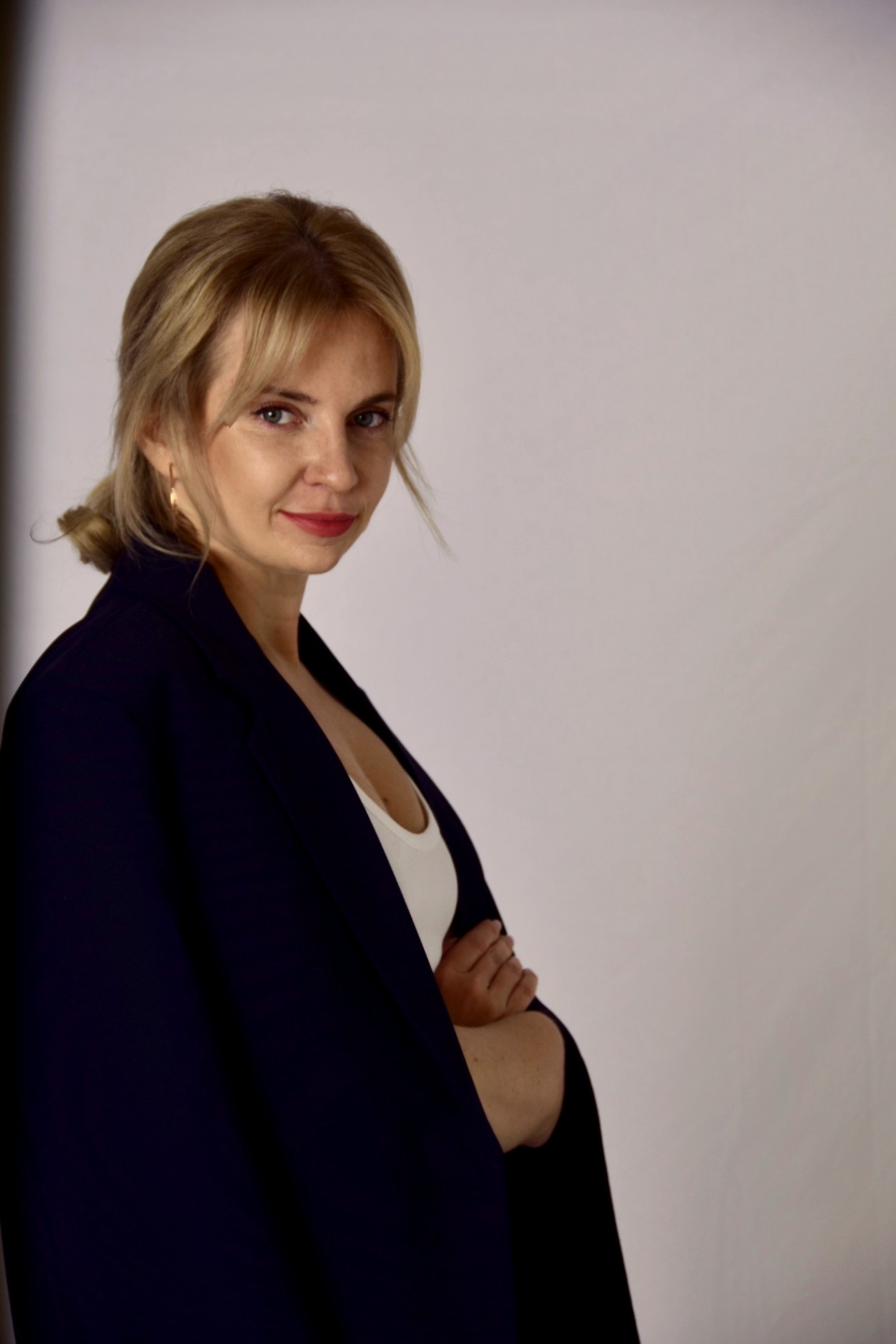 Portrait of Inna Melnyk, psychoanalytic counsellor, in a dark blazer against a soft grey backdrop